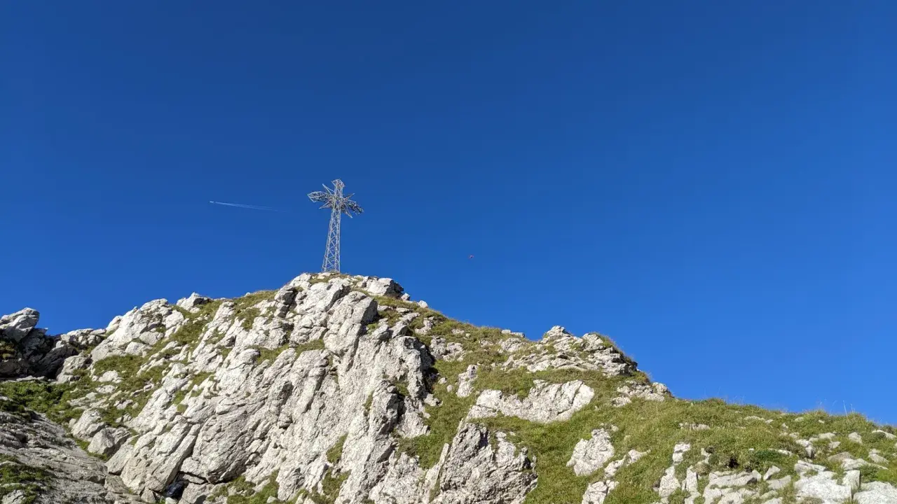 Kamienista trasa na Giewont prowadzi pod górę, gdzie widać krzyż na szczycie.