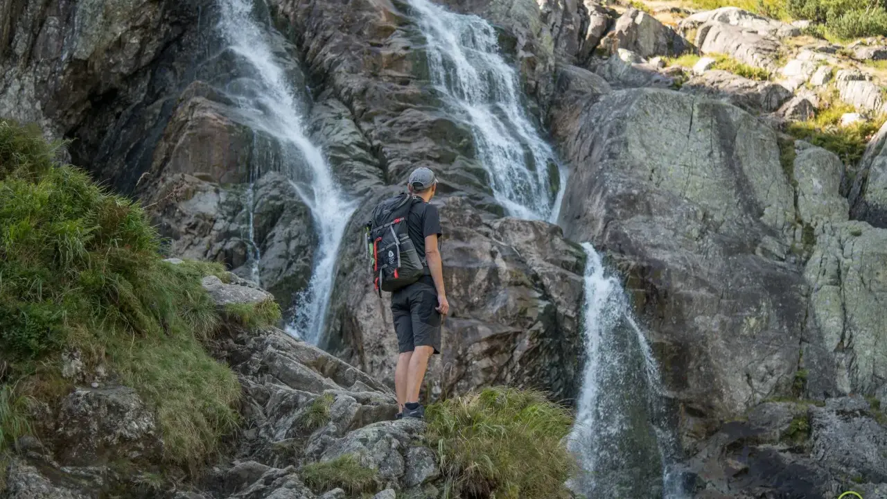 Turysta podziwia wodospad w Tatrach. Wspaniałe widoki, gdzie w Tatry zabierają nas górskie szlaki.
