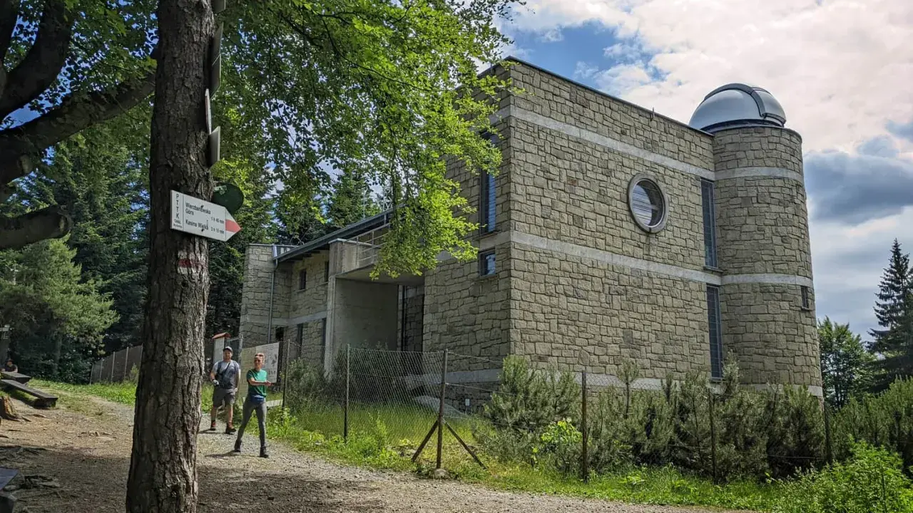 Obserwatorium astronomiczne na Lubomirze, kamienny budynek z kopułą, obok szlak turystyczny.