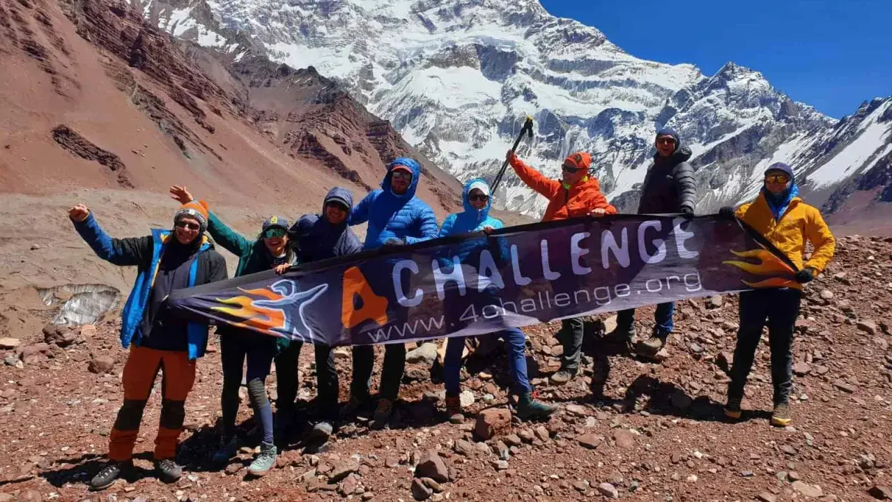 Grupa zdobywców z banerem "4 CHALLENGE" na tle majestatycznych gór z Aconcagua.