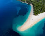 Widok z lotu ptaka na Zlatni Rat w Chorwacji. Plaże otoczone turkusowym morzem i zielonym lasem.