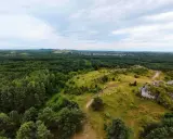 Krajobraz z wapiennymi ostańcami i ścieżkami na tle lasów i miasteczka. Jura Krakowsko-Częstochowska zachwyca zielenią i skalnymi formacjami.