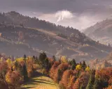 Jesienne góry w kolorach złota i czerwieni. Dym unosi się z doliny, tworząc mglistą atmosferę. Idealne miejsce, gdzie w góry jesienią.