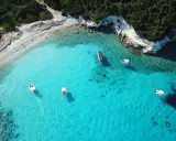 Idealne wakacje na Paxos: turkusowa woda, białe skały i łodzie unoszące się na falach.