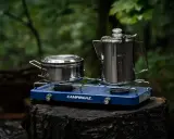 Jaka kuchenka turystyczna Campingaz z dwoma palnikami, garnkiem i kawiarką, gotowa do użycia w lesie.