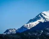 Majestatyczne szczyty Alp, pokryte śniegiem, z błękitnym niebem. Widok na trasę Tour du Mont Blanc.