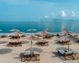 Pusta, słoneczna plaża na Kos, z rzędami leżaków i parasoli z trawy, czeka na gości.