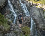 Turysta podziwia wodospad w Tatrach. Wspaniałe widoki, gdzie w Tatry zabierają nas górskie szlaki.