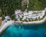 Widok z lotu ptaka na Hvar camping: białe domki, basen, plaża i turkusowe morze. Idealne miejsce na wakacje.