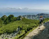 Dwie osoby z plecakami podziwiają widok na Tatry. Szlak jest kamienisty, ale stanowi łatwe zejście z Kasprowego Wierchu.