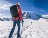 Alpinista z czekanem w ręku, ucząc się, jak trzymać czekan, na tle ośnieżonych gór.