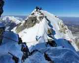 Grupa turystów na ośnieżonym szczycie. Widok na zimowe Tatry dla średniozaawansowanych.