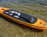 Pomarańczowy aquamarina sup z wiosłem leży na płytkiej, przejrzystej wodzie.