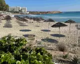 Plaża na Cyprze z rzędami parasoli i hotel w tle. Idealne miejsce na relaks na jednych z cypr best beaches.