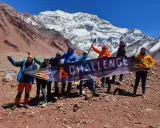 Grupa zdobywców z banerem "4 CHALLENGE" na tle majestatycznych gór z Aconcagua.