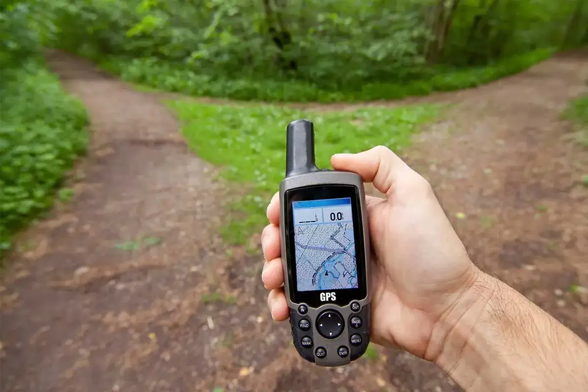 Ręka trzyma GPS, który pokazuje mapę. To może być początek przygody z geocachingiem, czyli poszukiwaniem skarbów.