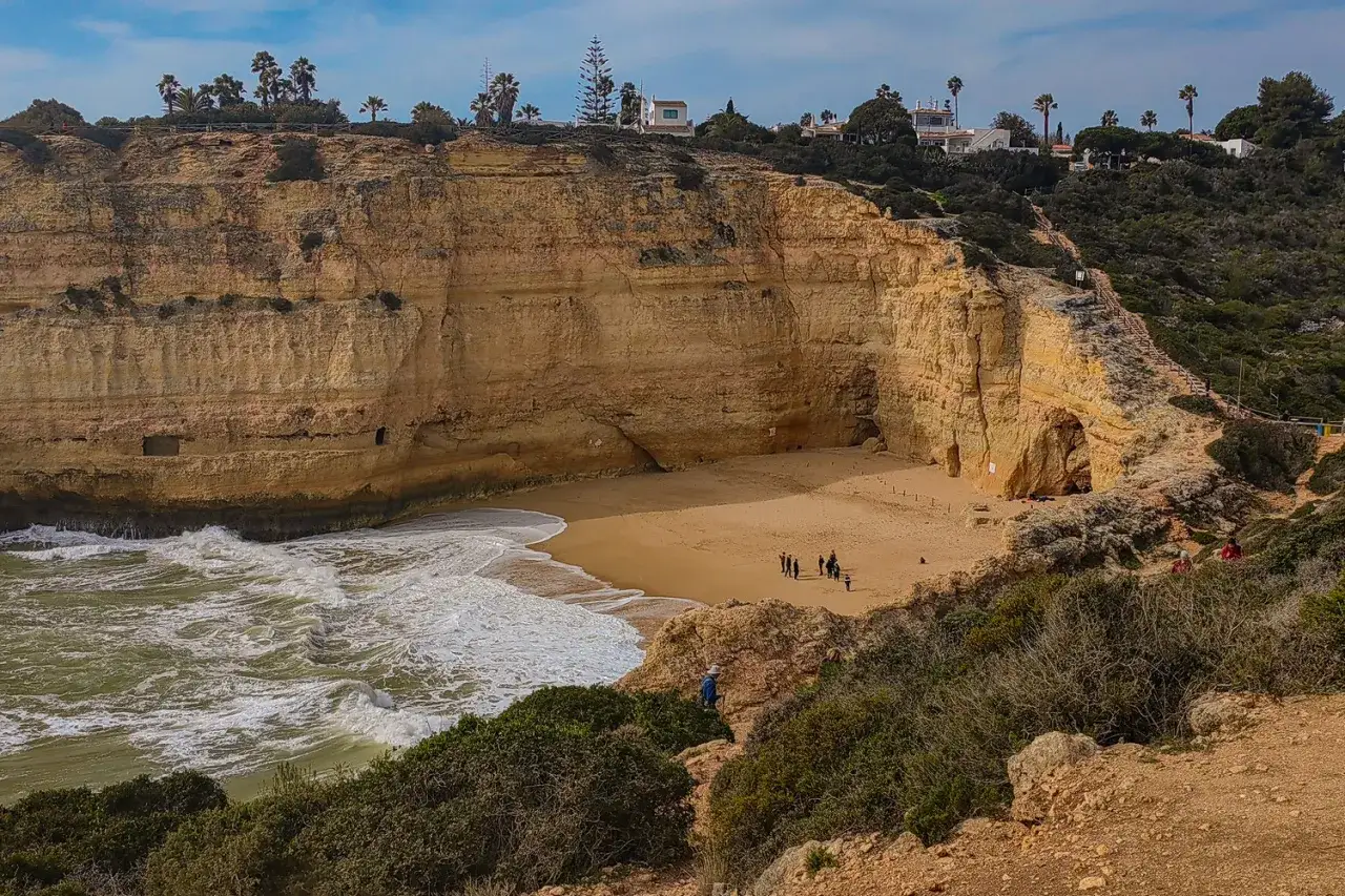 Malownicza plaża z klifami i jaskiniami, gdzie fale Atlantyku obmywają brzeg. To urokliwe portugalia wybrzeże algarve, idealne na spacer.