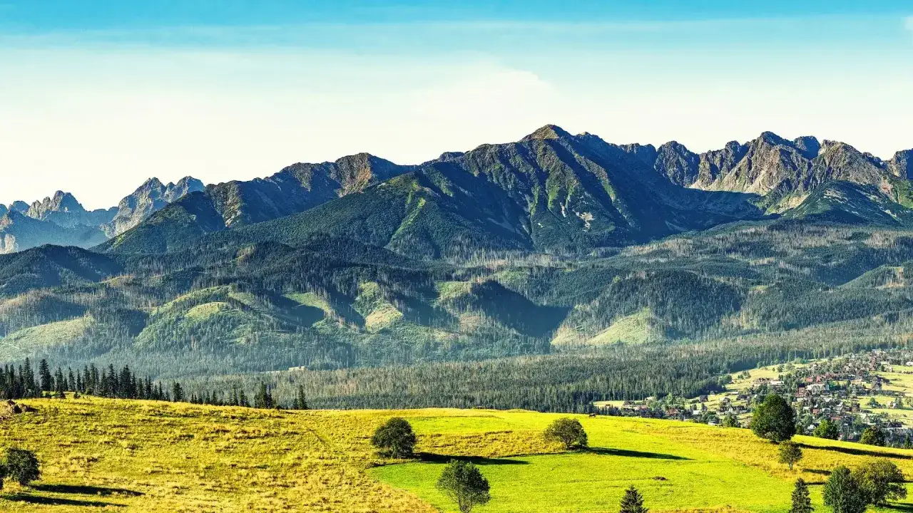 Widok na Tatry z zielonymi łąkami i lasami. Idealne miejsce, by zastanowić się, gdzie w Tatry wybrać się na wędrówkę.