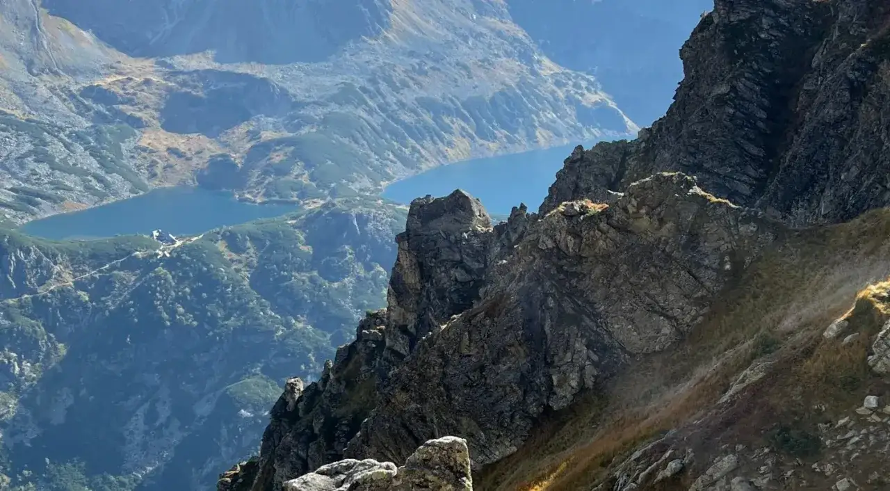 Skaliste szczyty i jezioro w jesiennym słońcu. Tatry w październiku zachwycają barwami.