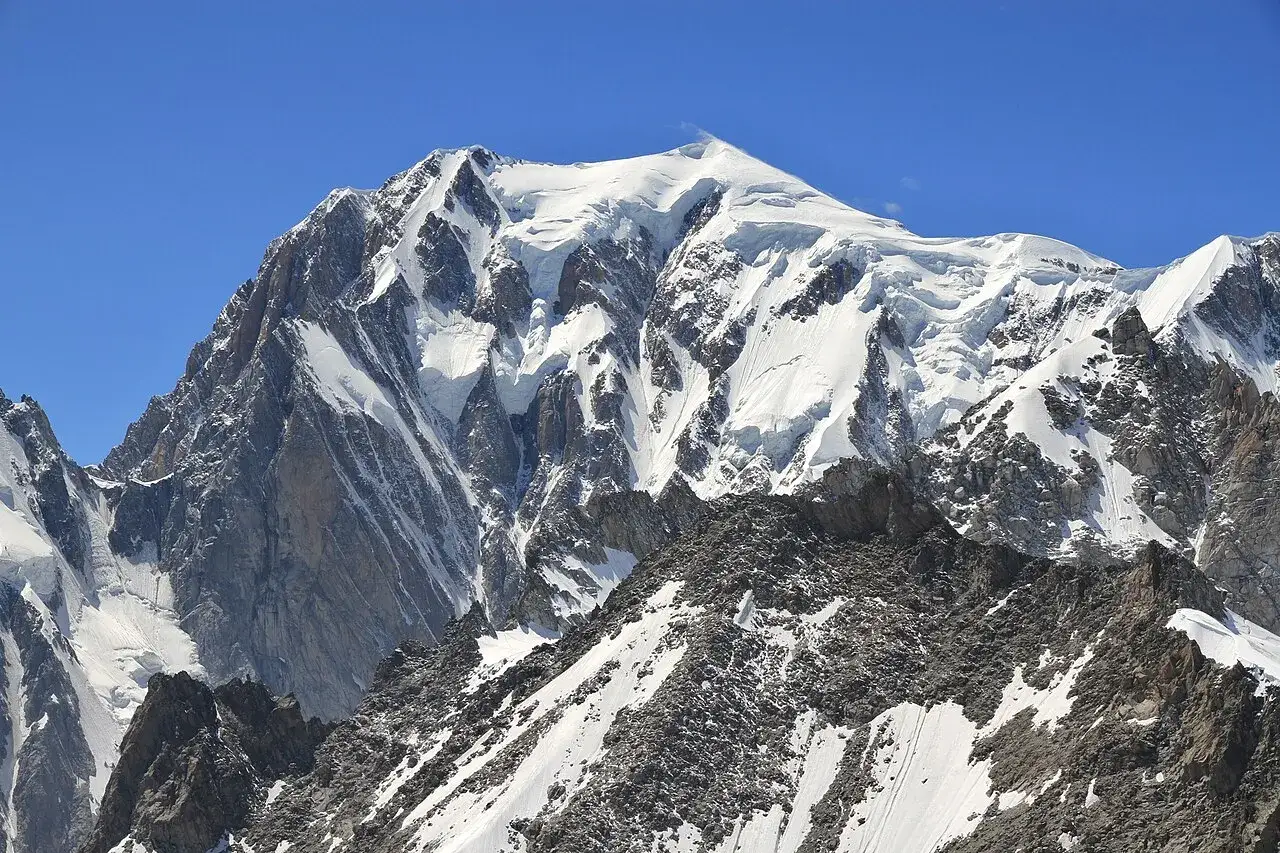 Majestatyczny Mont Blanc, najwyższy szczyt Alp, rozciąga się na granicy Francji i Włoch. Jego ośnieżone zbocza lśnią w słońcu.