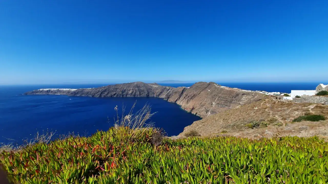Widok na kalderę Santorini z błękitnym morzem i białymi domkami na klifie.