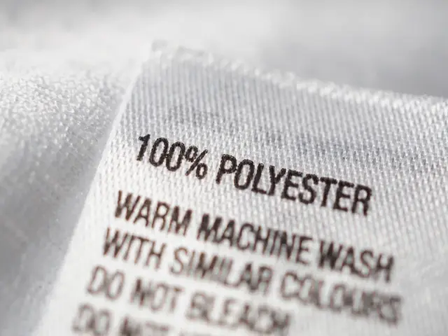 Metka odzieżowa z napisem "100% POLYESTER". Materiał ten, w przeciwieństwie do poliamidu, jest trwały i łatwy w pielęgnacji.