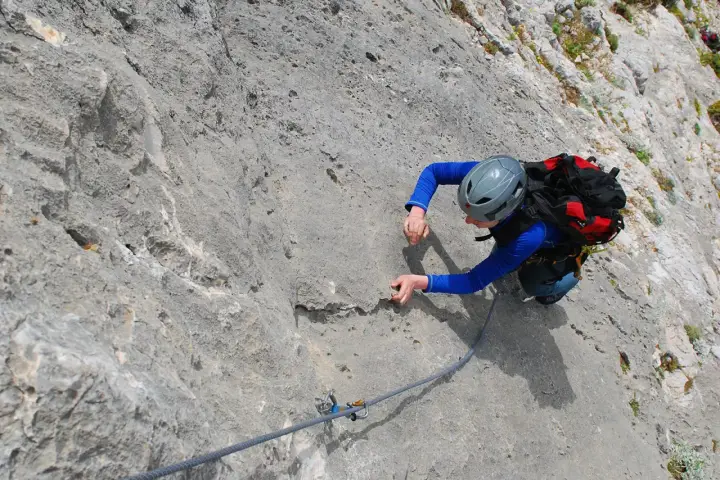 Wspinaczka na Kalymnos: wspinaczka po skalnej ścianie z liną asekuracyjną.