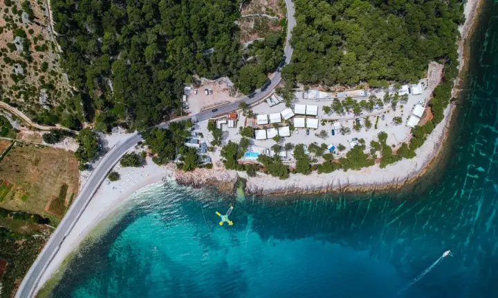 Widok z lotu ptaka na Hvar camping: białe domki, basen, plaża i turkusowe morze. Idealne miejsce na wakacje.